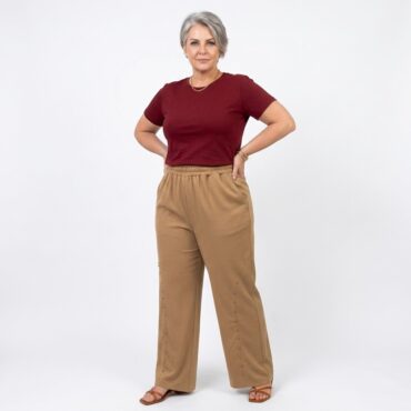 pantalon ample femme taille haute elastique fluide beige porté par une femme 60 ans aux cheveux poivre et sel, associée à un t-shirt bordeaux rentré dans la ceinture.
